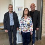 Μπροστα απο την αφίσα της ημερίδας είναι όρθιοι απο τα αριστερά ο Αντιπρόεδρος της Περιφερειακής Σωτήρης Κατσαρος,η Γενική Γραμματέας Έλενα Σταύρου και ο πρόεδρος Σιώτος Απόστολος.