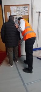 Στέλεχος της παράστασης απεικονίζεται να δείχνει σε μέλος της Περιφερειακής τα σκηνικά.